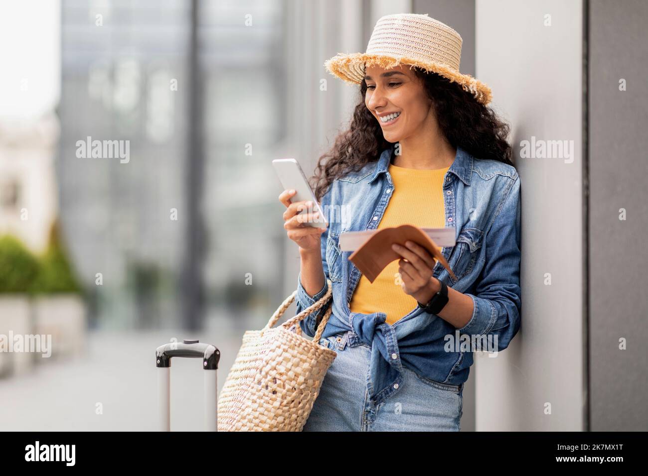 Positive middle eastern woman standing by airport, using smartphone Stock Photo