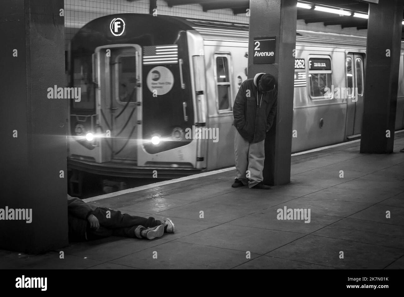 A grayscale of the people standing and lying in the New York City