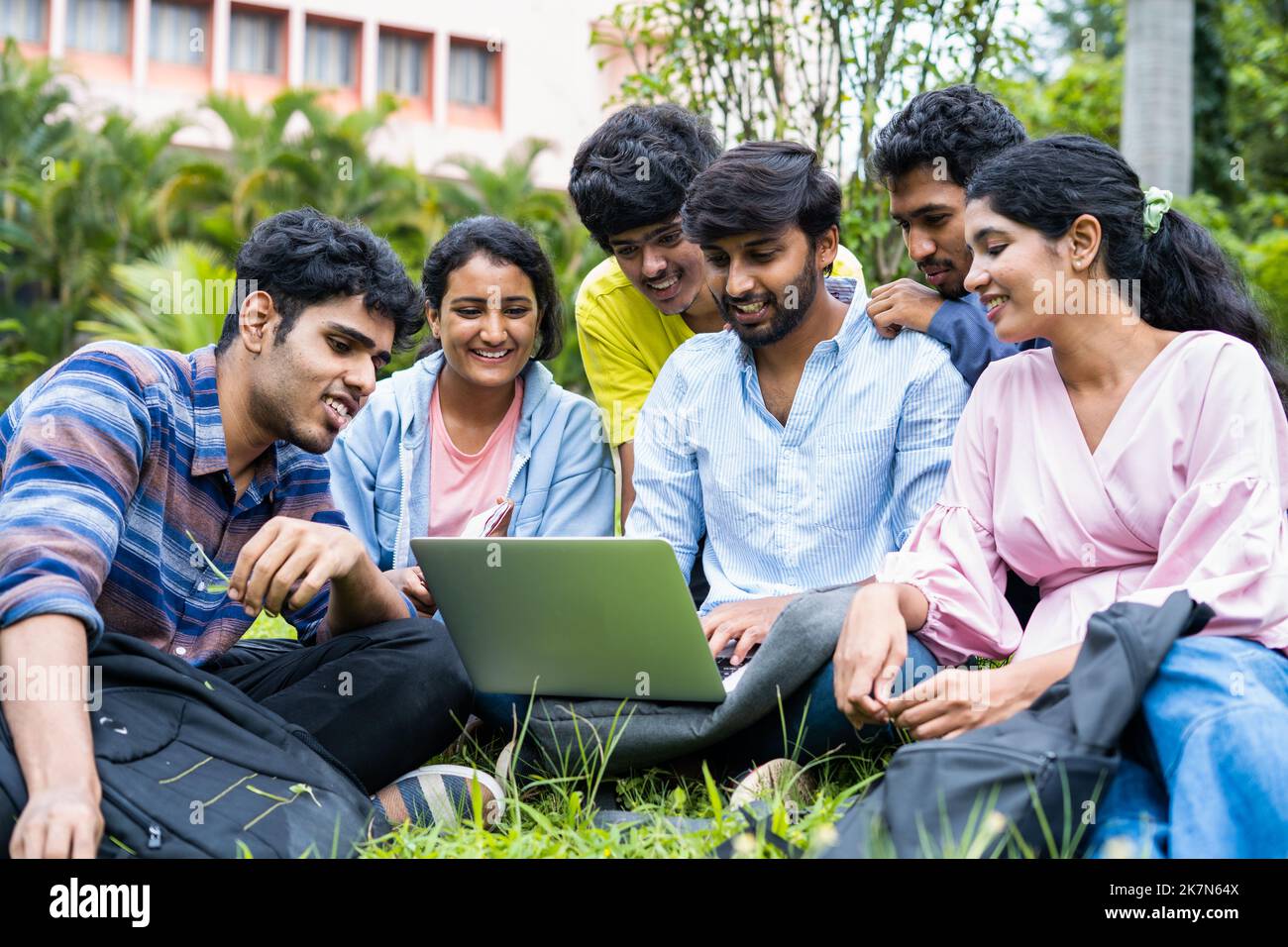 group of young students checking exam results or waiting for project approval on laptop at collage campus - concept of teamwork, bonding and Stock Photo