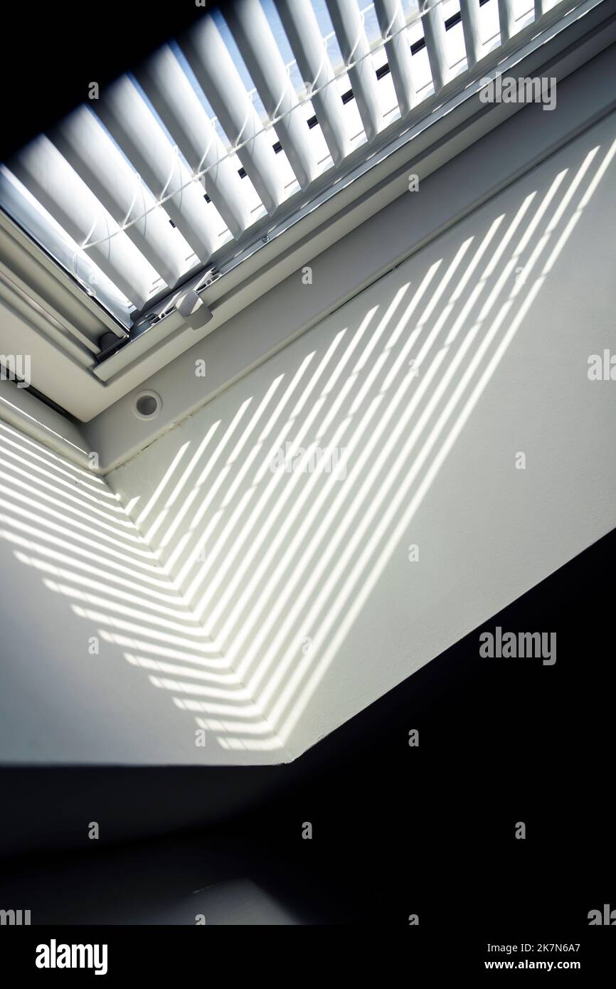 A side portrait of a velux roof window with a closed jalousie in it to keep the warmth out or to keep the light from entering the room in the morning Stock Photo