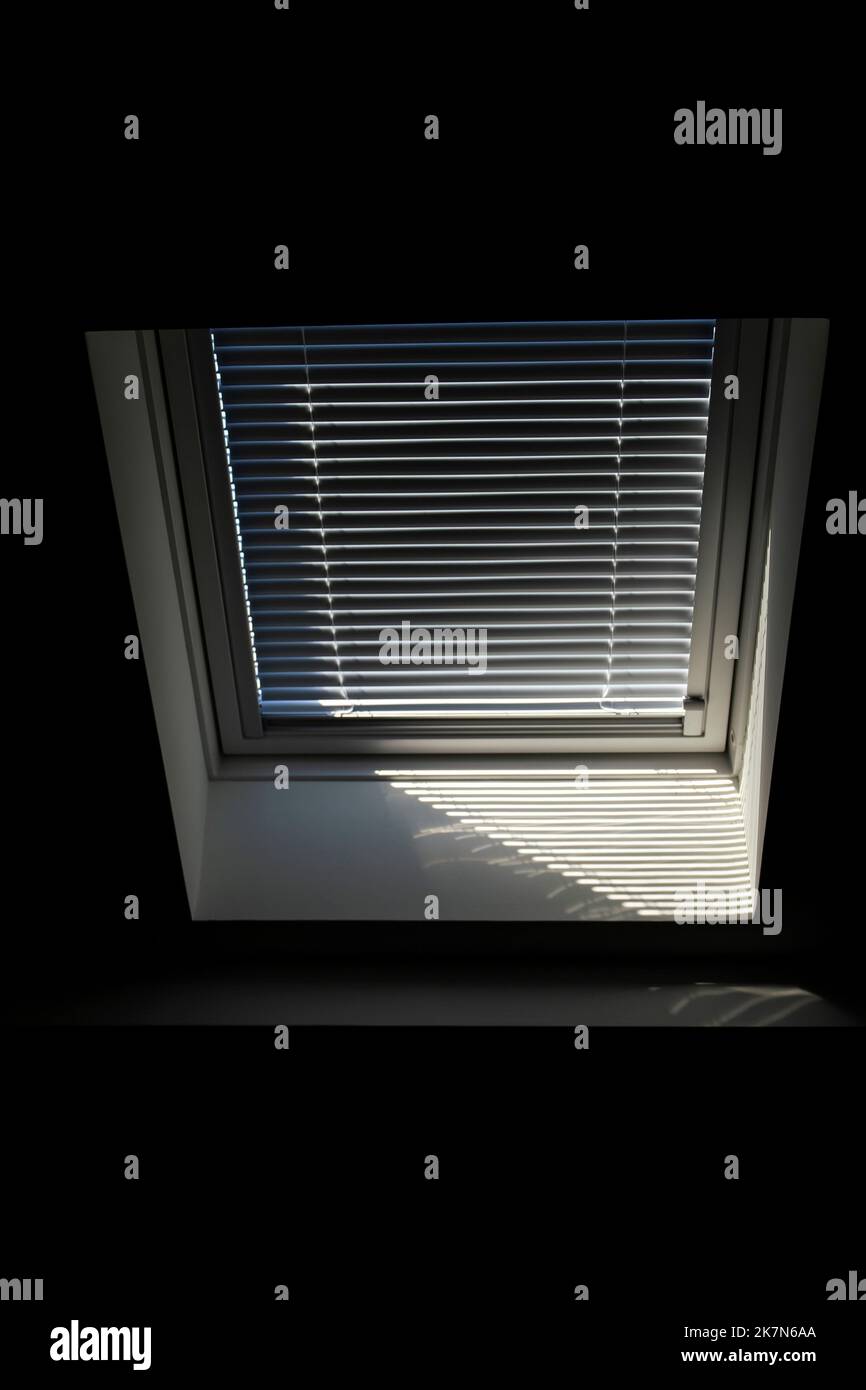 A front portrait of a velux roof window with a closed jalousie in it to keep the sun and warmth out or to keep the light from entering the room in the Stock Photo