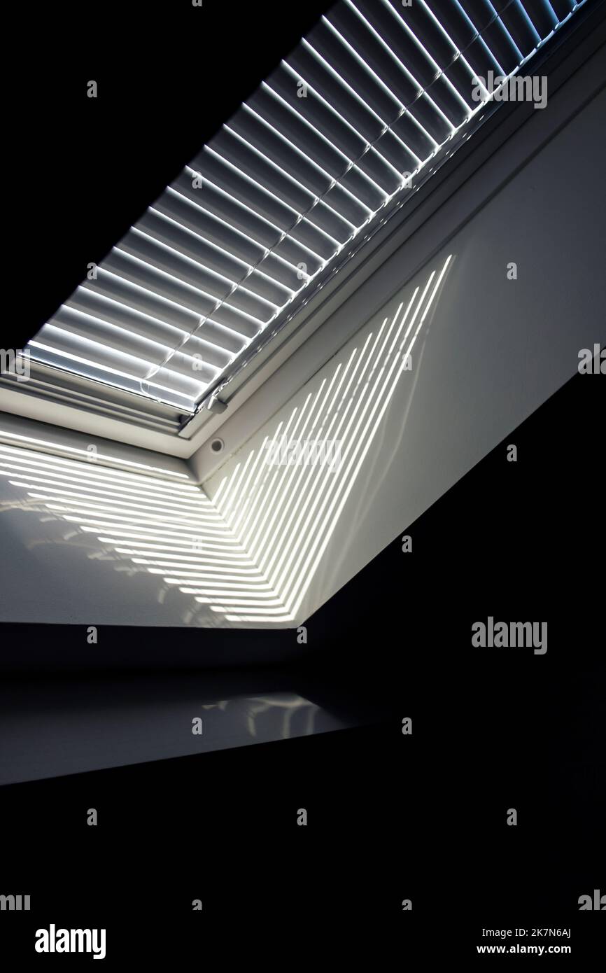 A side portrait of a velux roof window with a closed jalousie in it to keep the sun and warmth out or to keep the light from entering the room in the Stock Photo