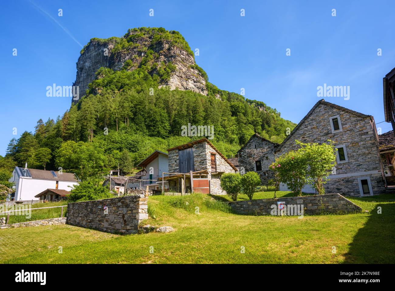 Traditional rustic stone alpine huts beneath a picturesque mountain in Brione village, Verzasca valley, Alps mountains, canton Ticino, Switzerland Stock Photo