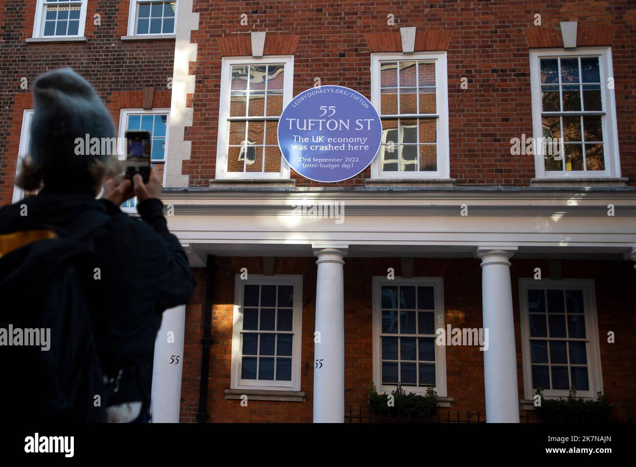 London, UK, 18 October 2022. A woman photographs a blue plaque on 55 Tufton Street in Westminster, which was attached by campaigners from Led By Donkeys. The building is home to several free market groups that were instrumental in Kwarsi Kwarteng's mini budget. Credit: David Mirzoeff/Alamy Live News Stock Photo