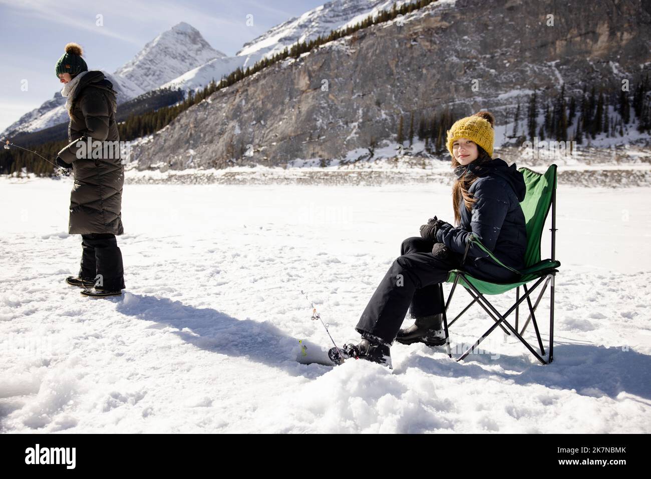 Girl ice fishing on frozen alpine lake Stock Photo Alamy
