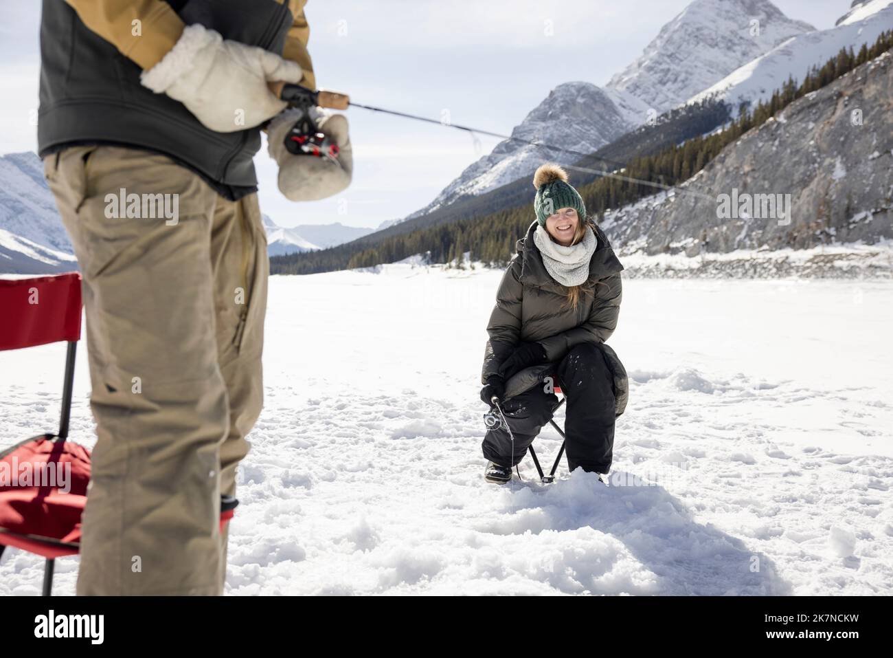 Woman ice fishing on frozen alpine lake Stock Photo Alamy