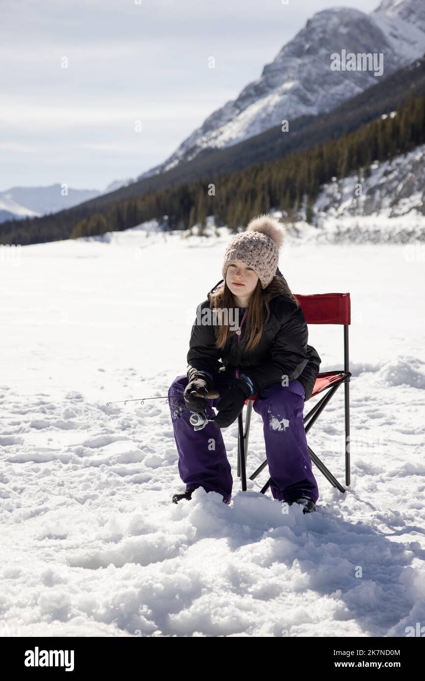 Girl ice fishing on frozen alpine lake Stock Photo Alamy