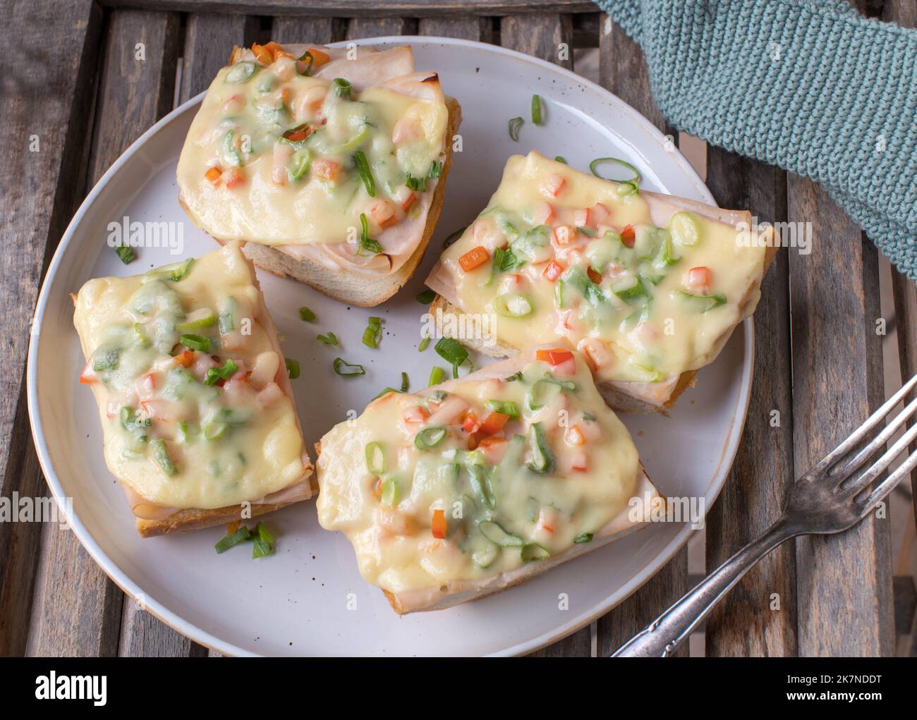 Open faced grilled ham and cheese sandwich with bell peppers and chives on french baguette Stock Photo