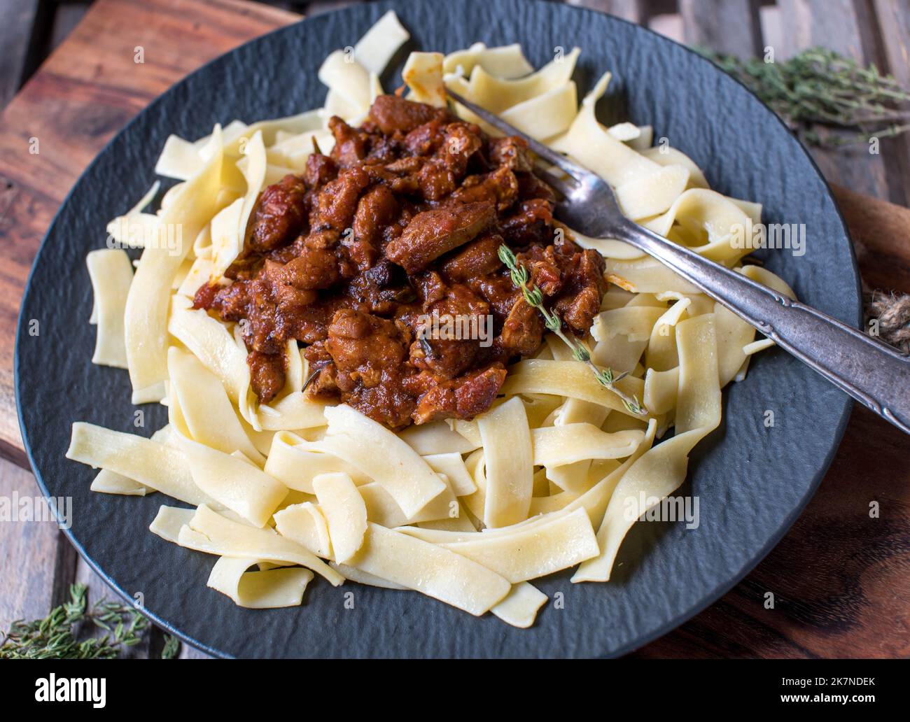 Brown stew chicken with tagliatelle on a plate. Italian cuisine Stock Photo