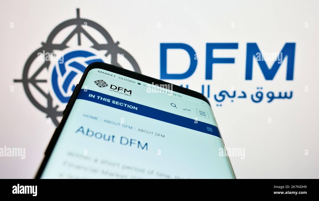 Smartphone with website of stock exchange Dubai Financial Market (DFM) on screen in front of business logo. Focus on top-left of phone display. Stock Photo