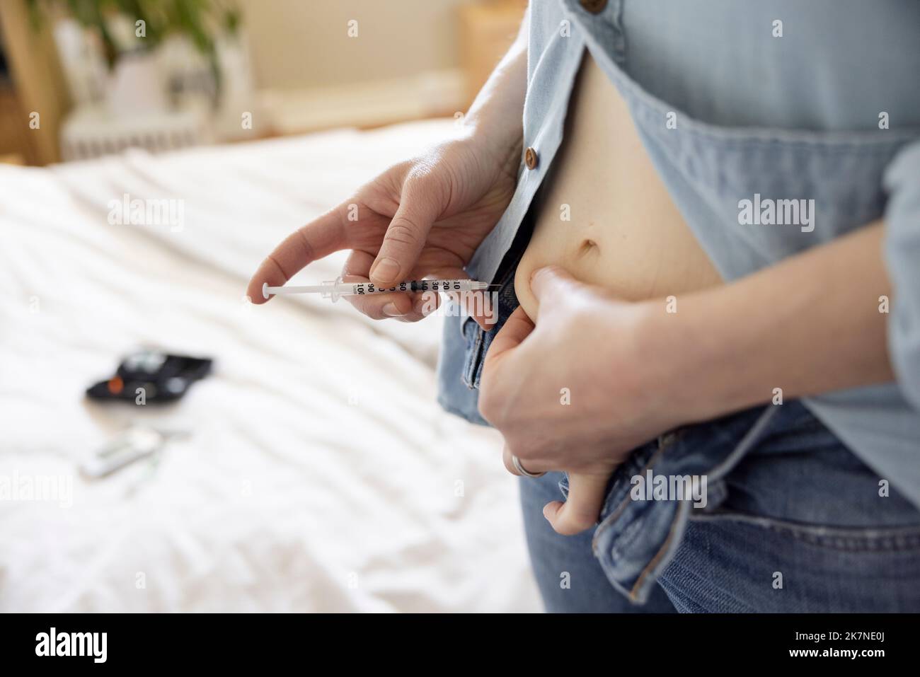 Close up woman with diabetes injecting insulin into stomach Stock Photo