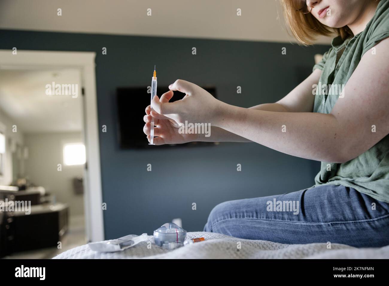 Teenage girl preparing diabetes insulin injection on bed Stock Photo