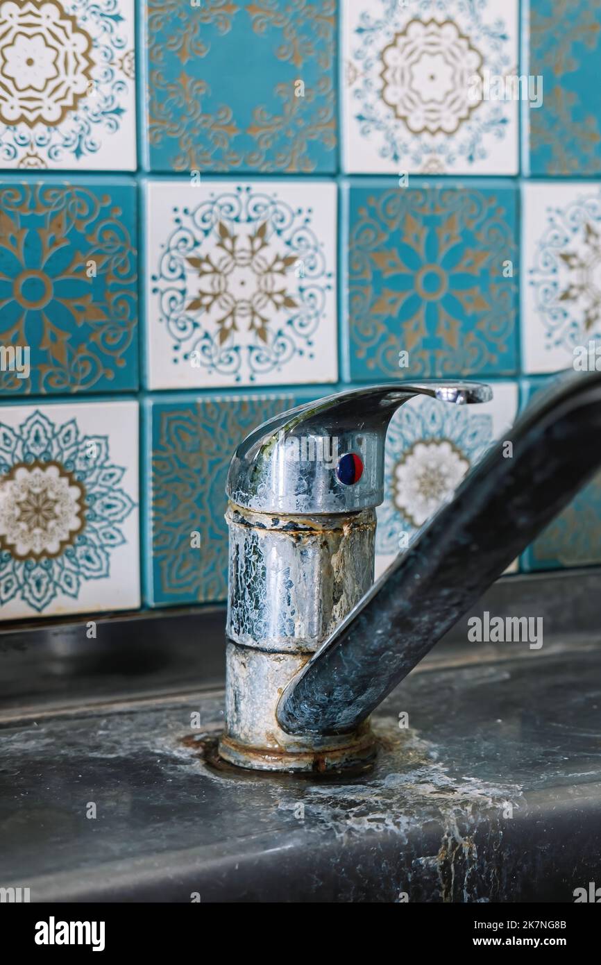 Old rusty sink faucet in kitchen. Rust streaks, calcium scale, hard