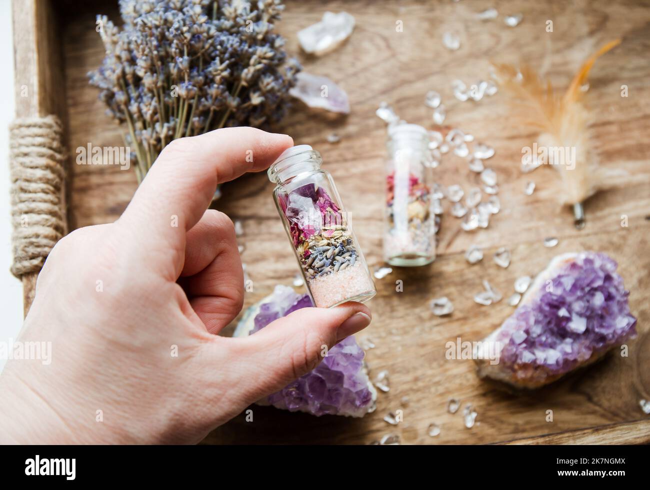 Woman hand holding homemade spell jar bottle with good intentions for home protection and inner balance. Filled with Himalayan salt, dried herbs. Stock Photo