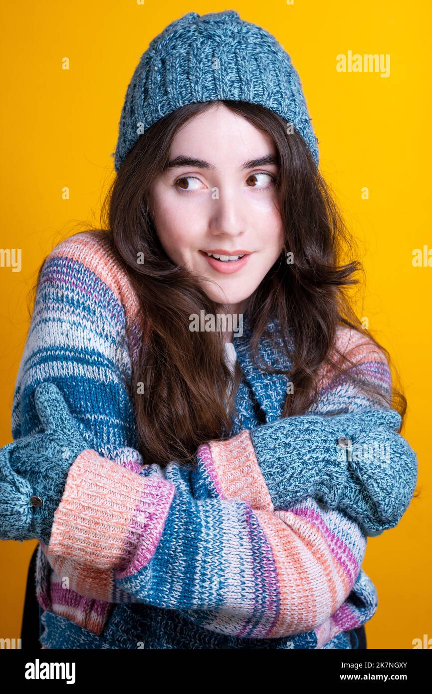 Portrait of a Young Woman in Knit Apparel Against Yellow Backdrop Stock Photo