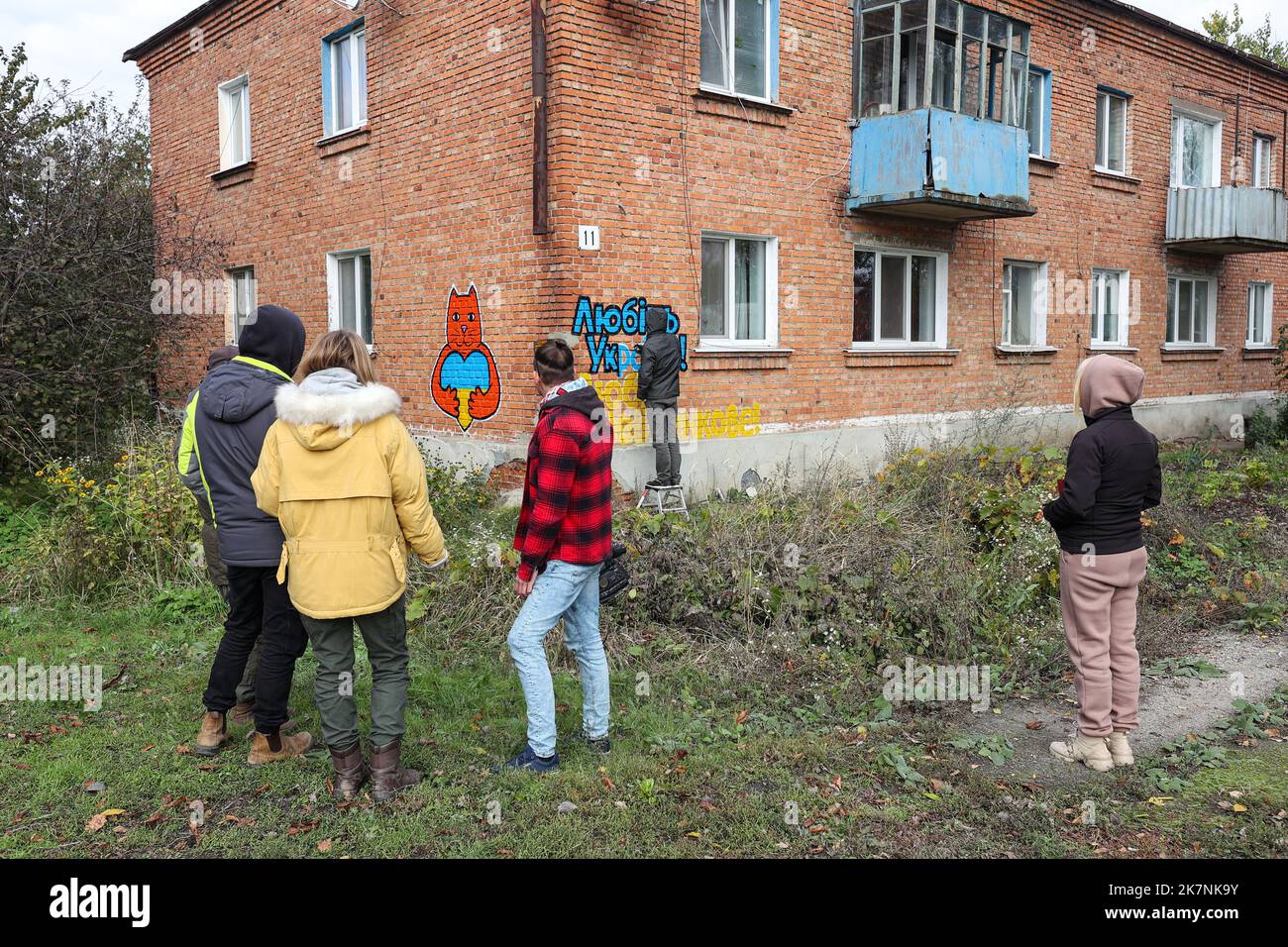 KHARKIV REGION, UKRAINE - OCTOBER 09, 2022 - Local residents watch artists create a mural as part of the 'Cultural Landing' campaign in Shevchenkove village, Kharkiv Region, northeastern Ukraine. Stock Photo