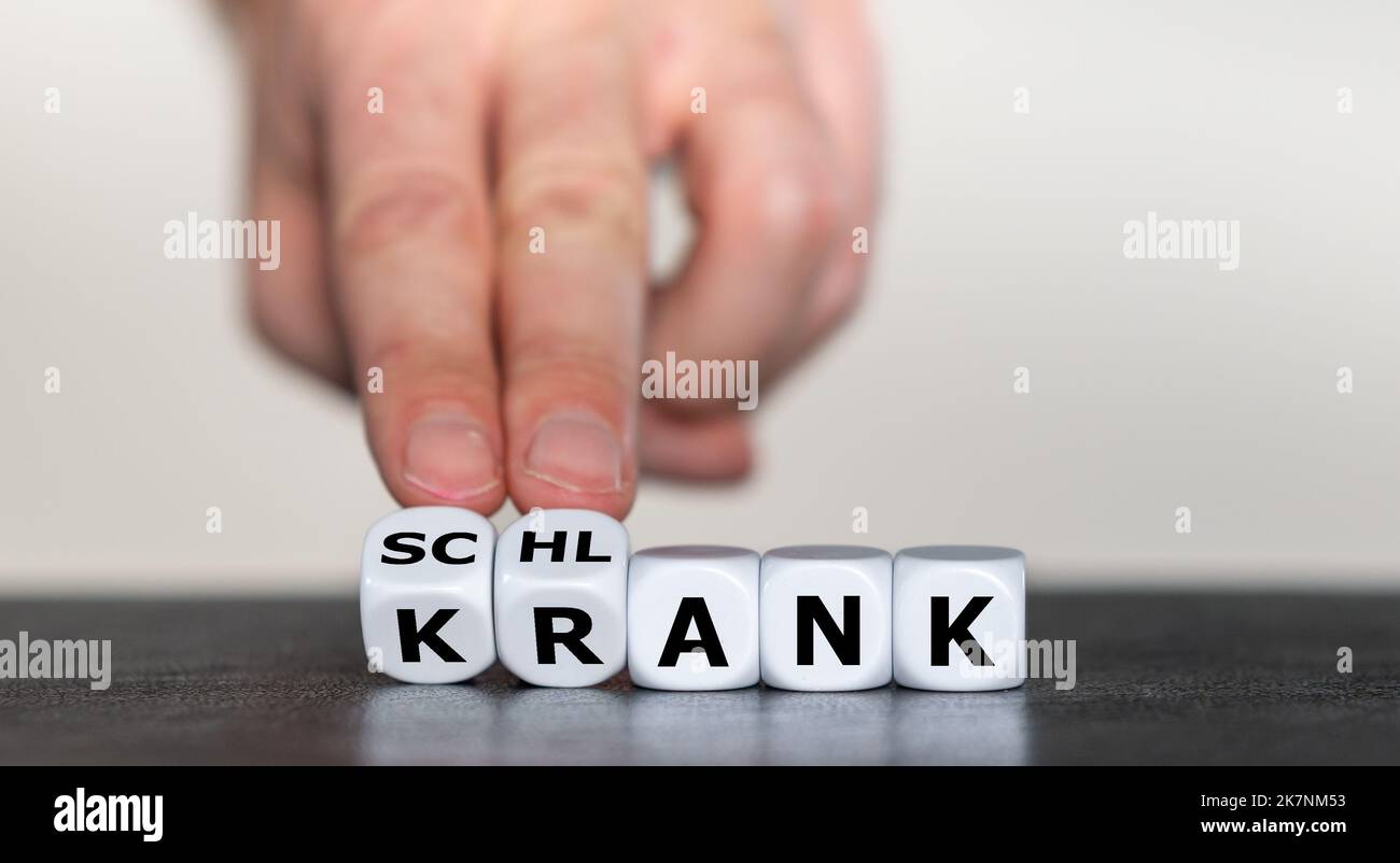 Hand turns dice and changes the German word 'krank' (sick) to 'schlank' (slim). Stock Photo