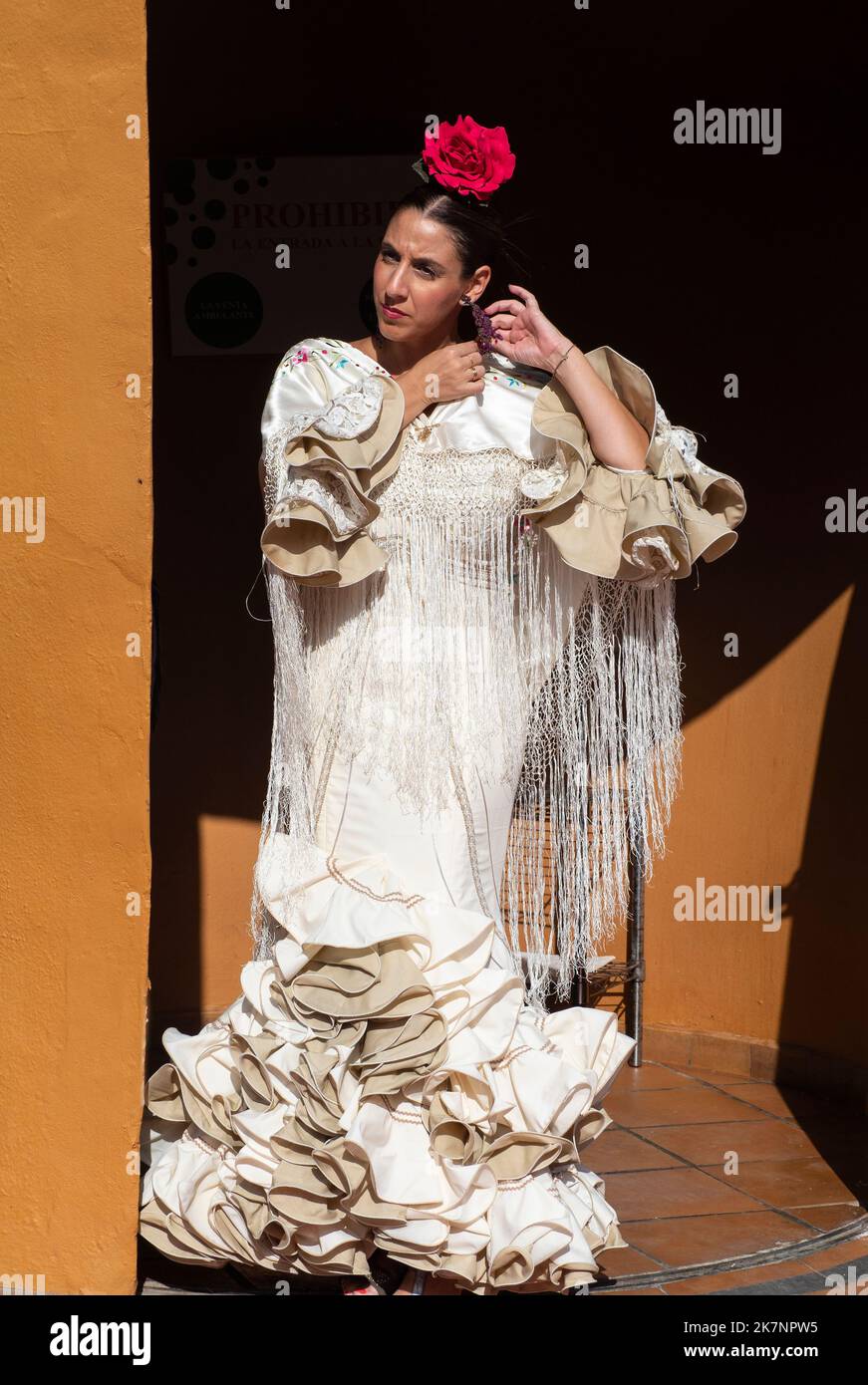 Young girl wearing the typical Andalusian gypsy dress at the door of a stand at the fair in Fuengirola. Stock Photo