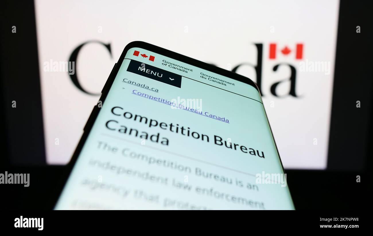 Mobile phone with web page of Canadian regulator Competition Bureau on screen in front of logo. Focus on top-left of phone display. Stock Photo