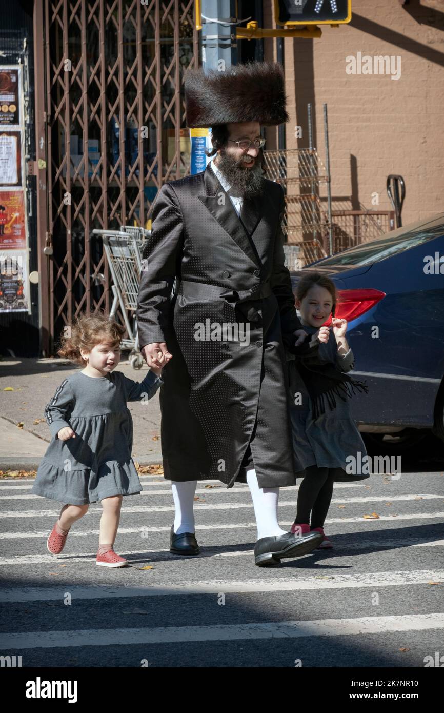 A Haasdic man wearing high white socks and a shtreimel walks with his 2 daughters on Lee avenue in Williamsburg. Stock Photo