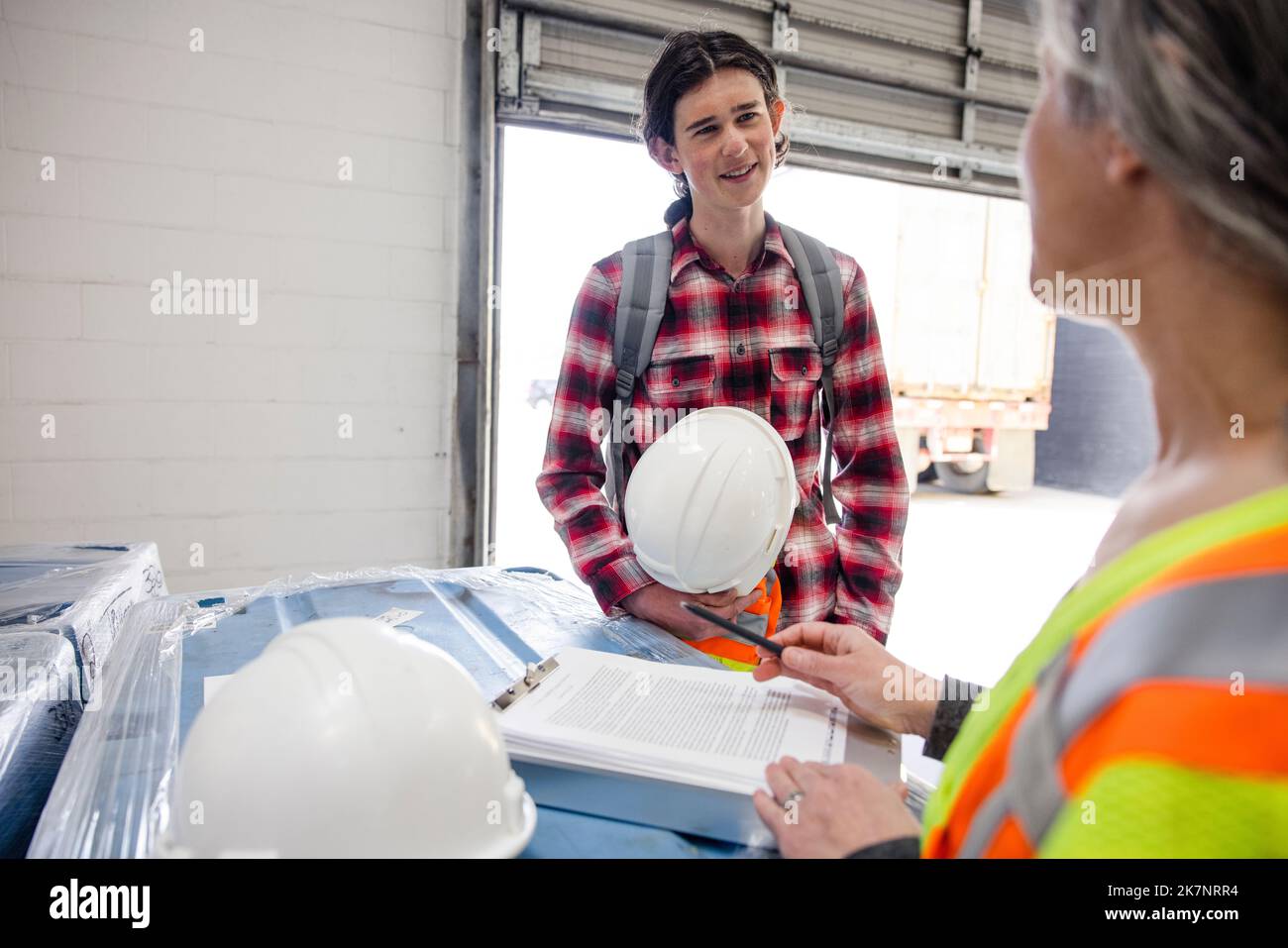 Manager training new employee with hard hat in warehouse Stock Photo