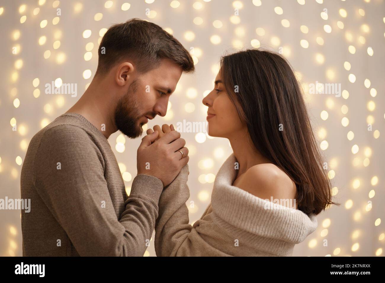 Two cheerful lovely sweet tender beautiful adorable cute romantic married spouses husband and wife looking to each other with lights in background Stock Photo