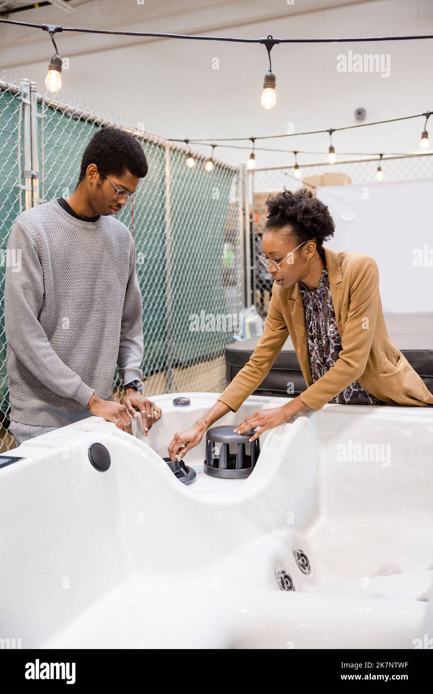 Saleswoman showing hot tub to customer in showroom Stock Photo Alamy