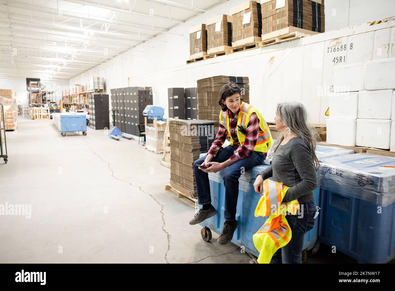 Warehouse workers with reflective vests talking Stock Photo