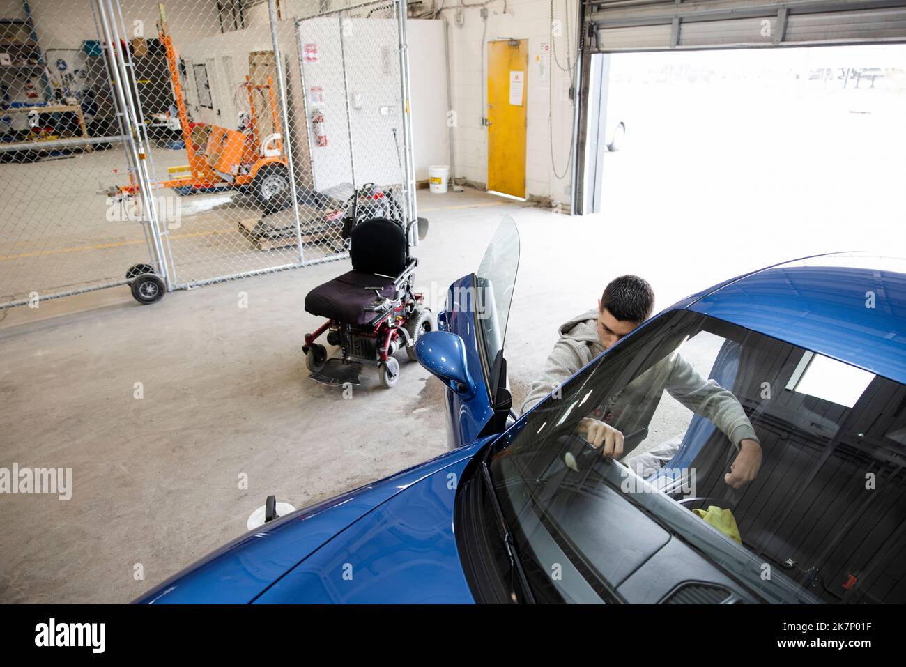 Disabled male worker detailing inside of sports car in auto body shop