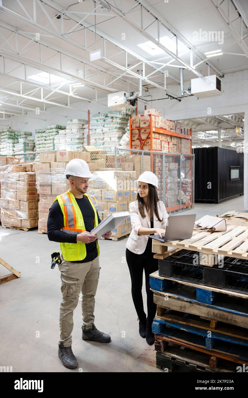 Warehouse managers with laptop and clipboard meeting Stock Photo