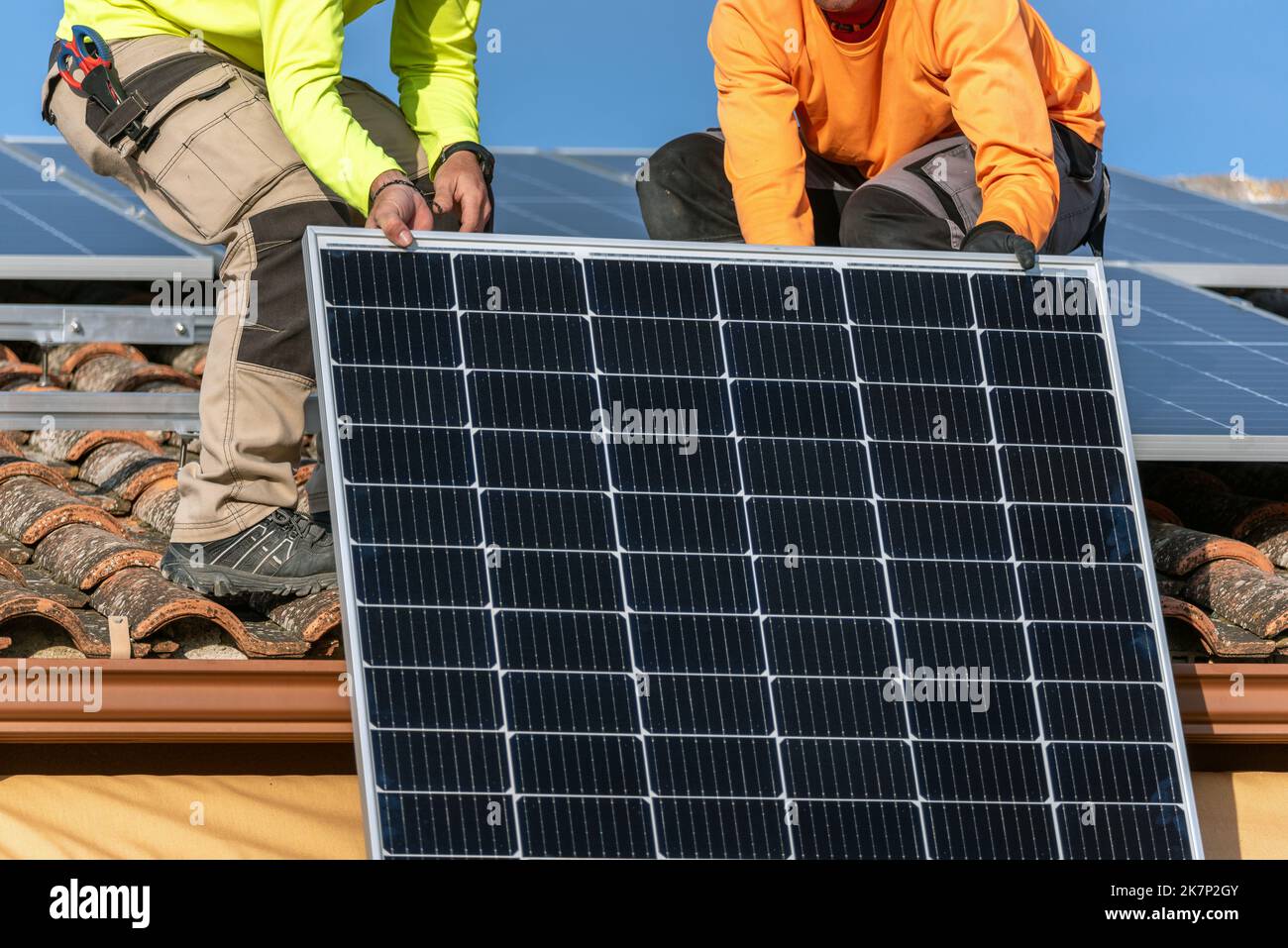 People Installing Roof with two people installing solar panels and a blue sky with white ...