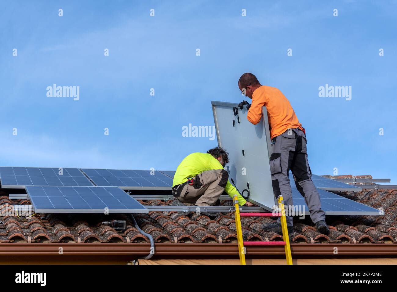 People Installing Roof with two people installing solar panels and a blue sky with white ...
