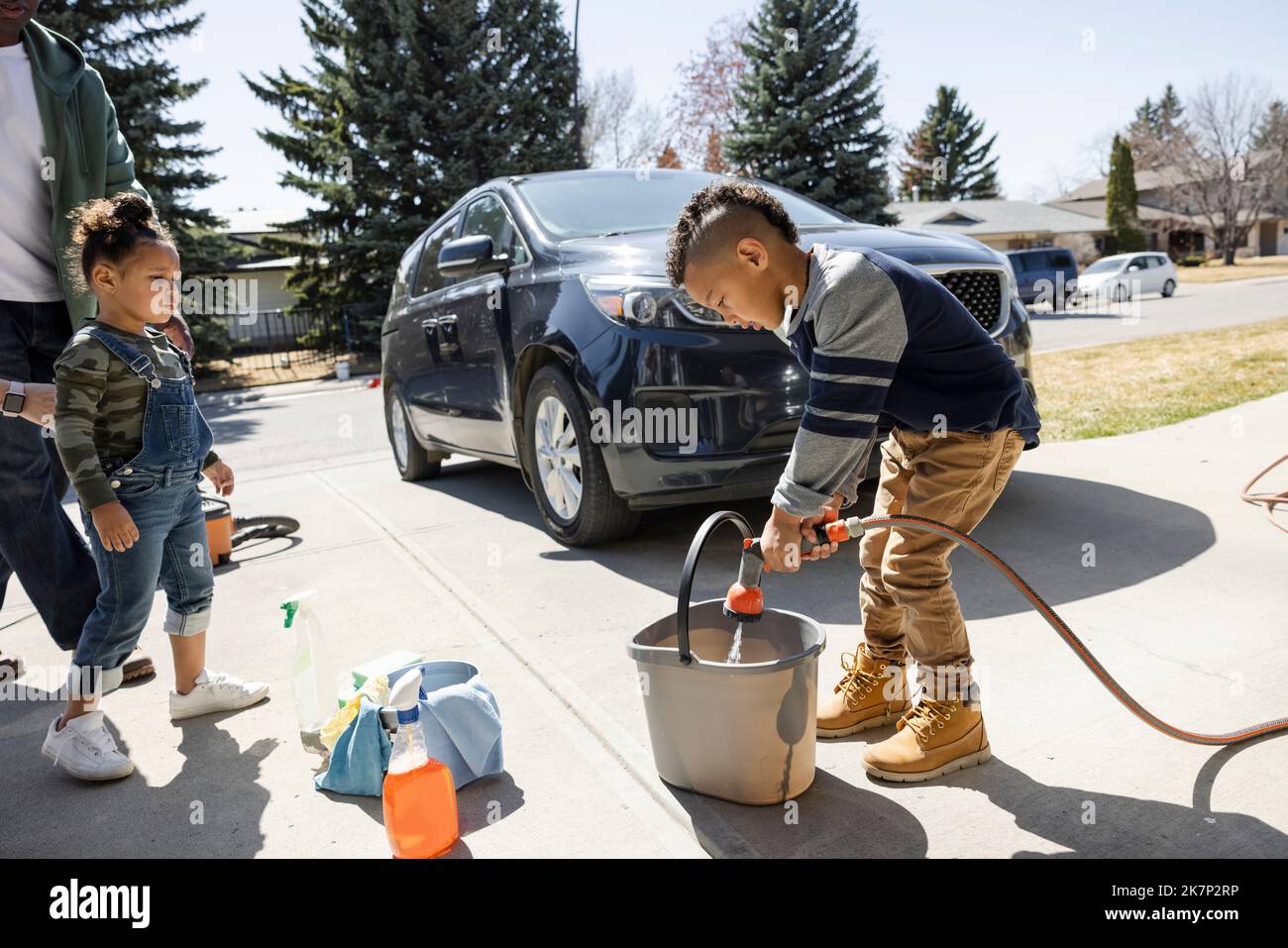 Boy filling bucket with water in driveway Stock Photo Alamy