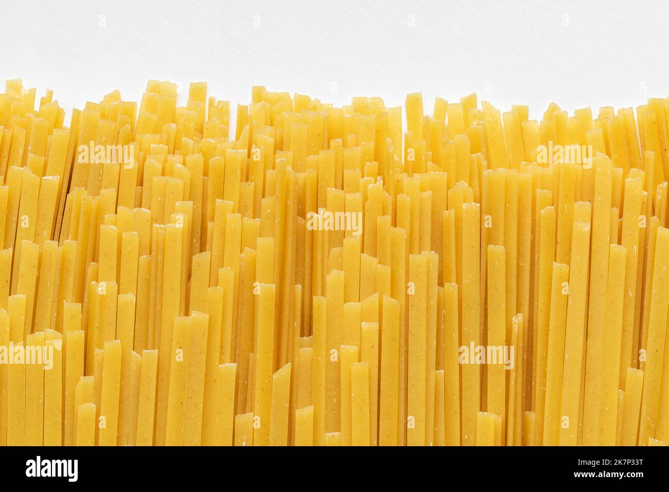 Uncooked dry durum fettuccine pasta on white background. Raw spaghetti or noodles Stock Photo