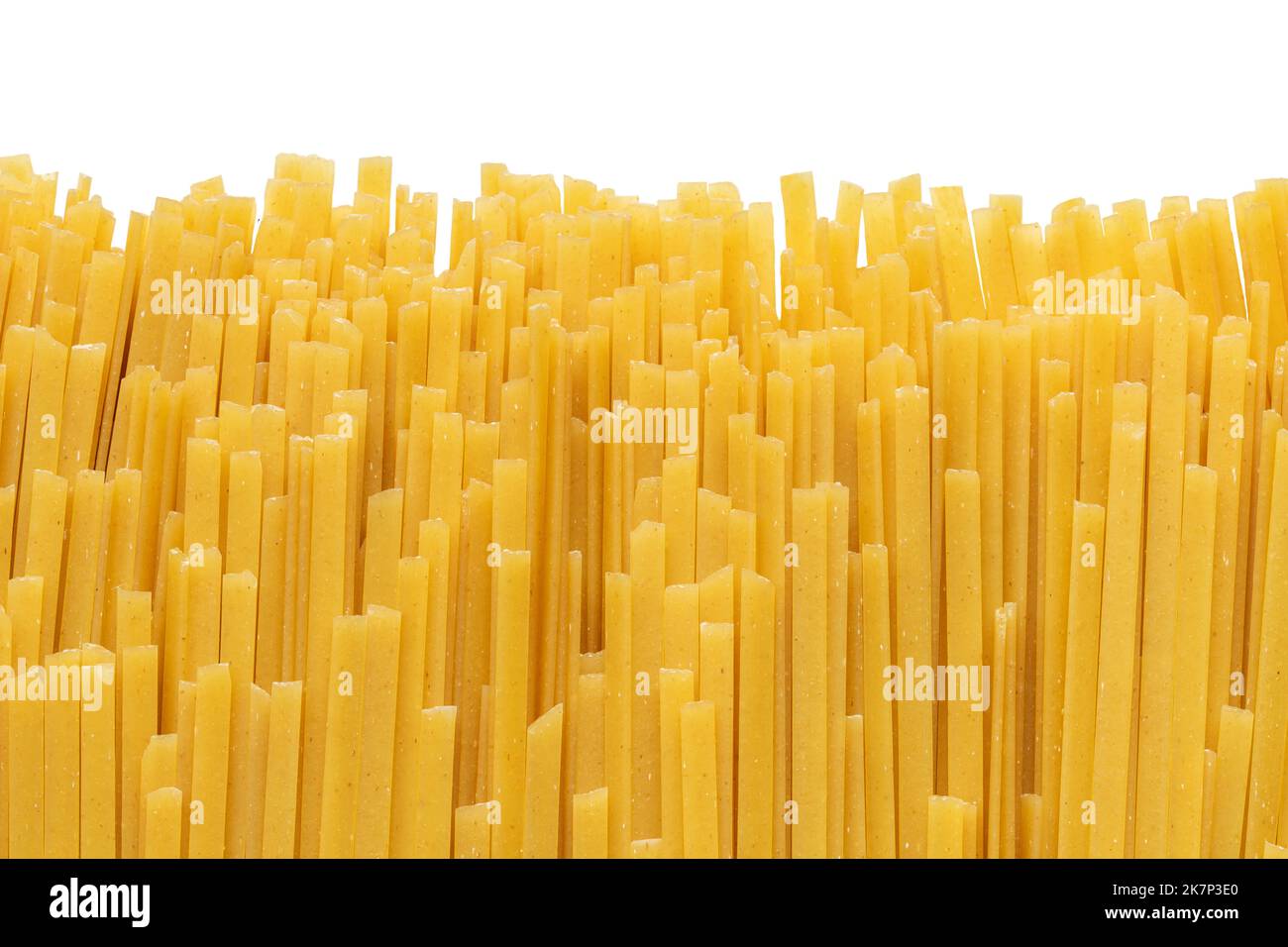 Pile of uncooked durum fettuccine pasta isolated on white background. Raw spaghetti or noodles