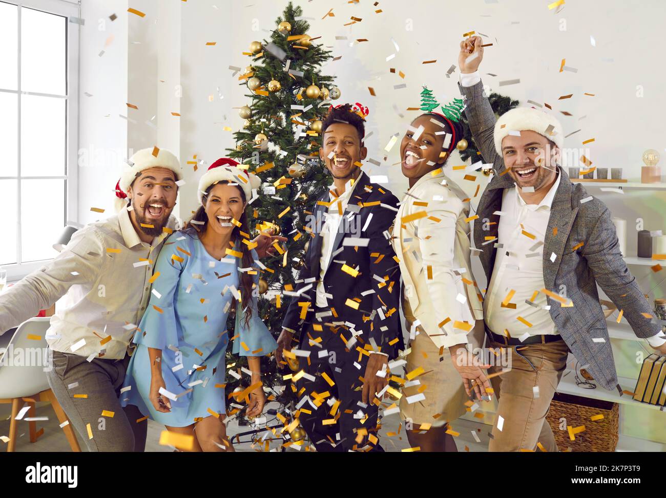 Positive colleagues having fun, laughing and throwing confetti at New Year corporate party in
