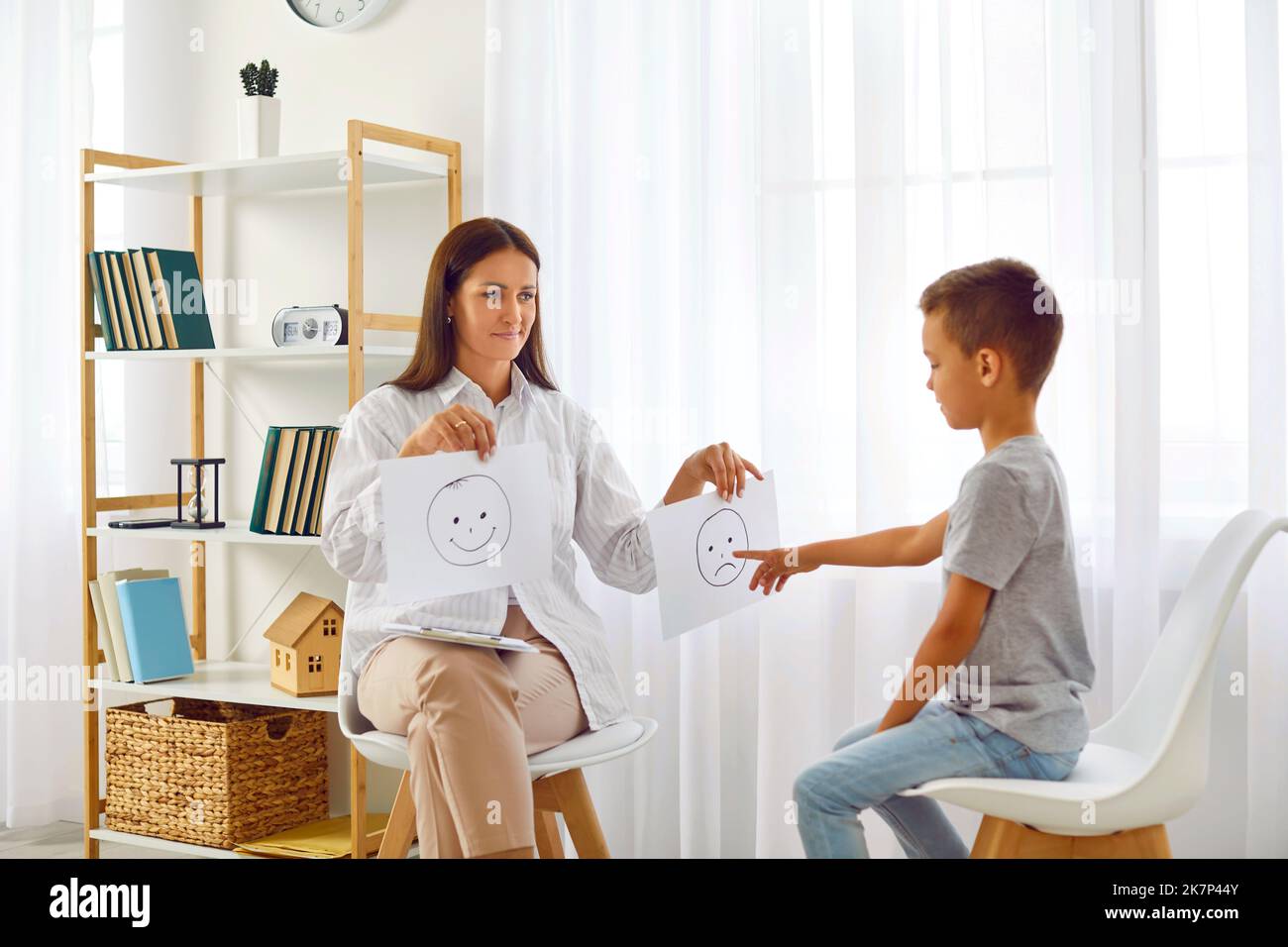 Psychologist or therapist uses emoji while talking with school child about emotions Stock Photo