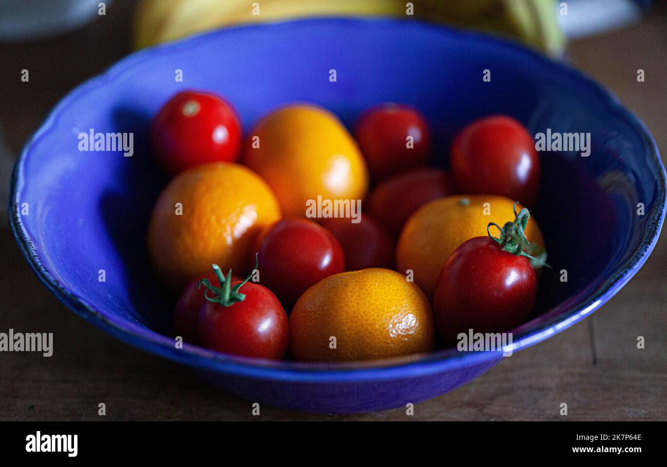 Cherry tomatoes and mandarins in a blue bowl. Stock Photo