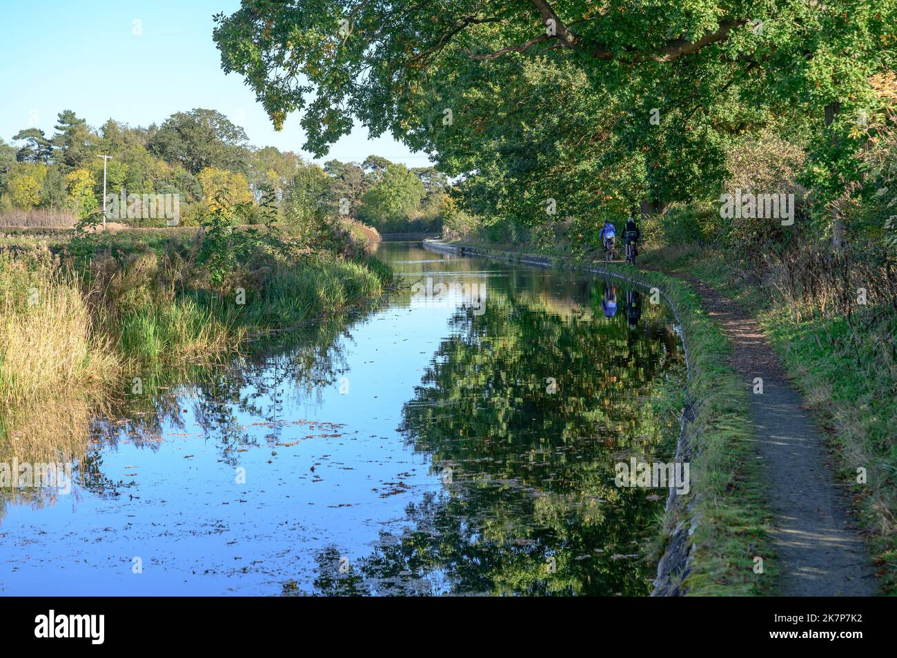 Two men cycle along the towpath of the Montgomery Canal in bright autumn sunshine. Stock Photo