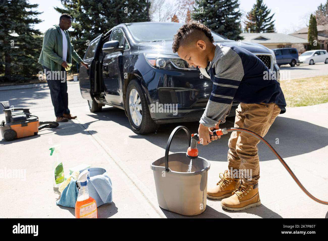 Boy filling bucket with water in driveway Stock Photo Alamy
