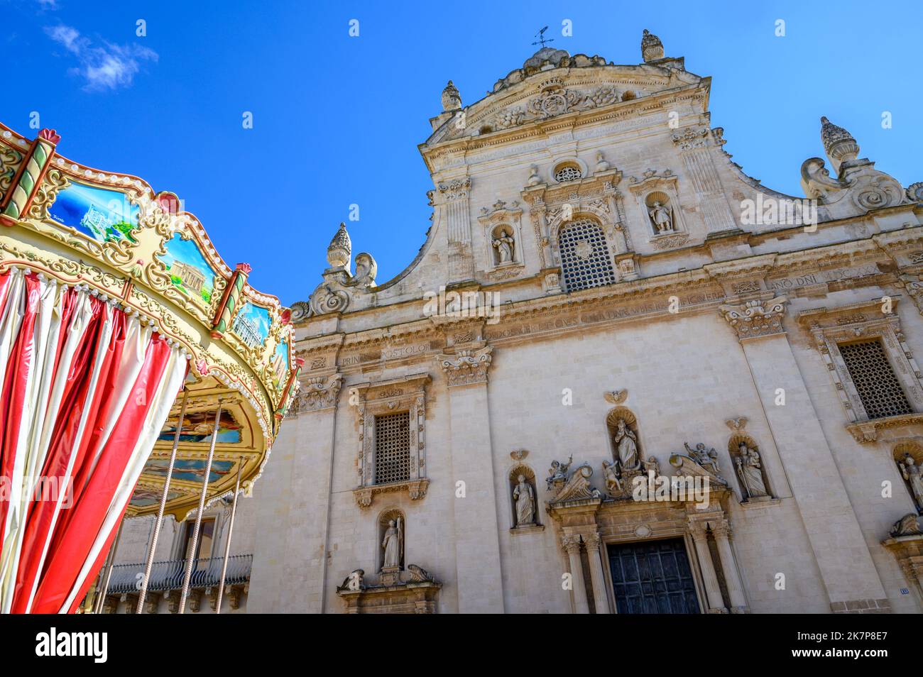Front of the baroque Church of Saints Peter and Paul the Apostles with a funfair carousel in the