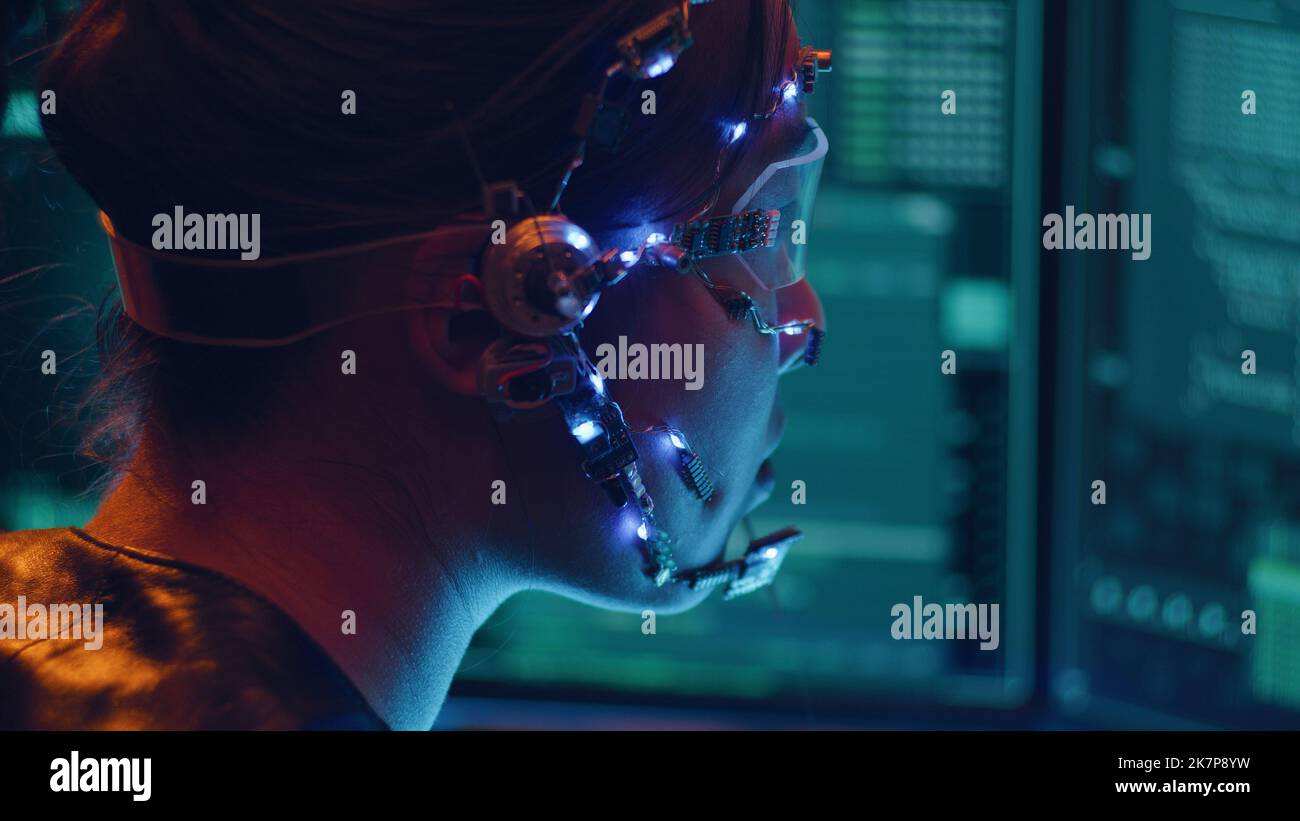Side view of an Asian girl with futuristic headset and microphone programming using multiple computer screen. Cyperpunk style. Sci-fi background. Stock Photo
