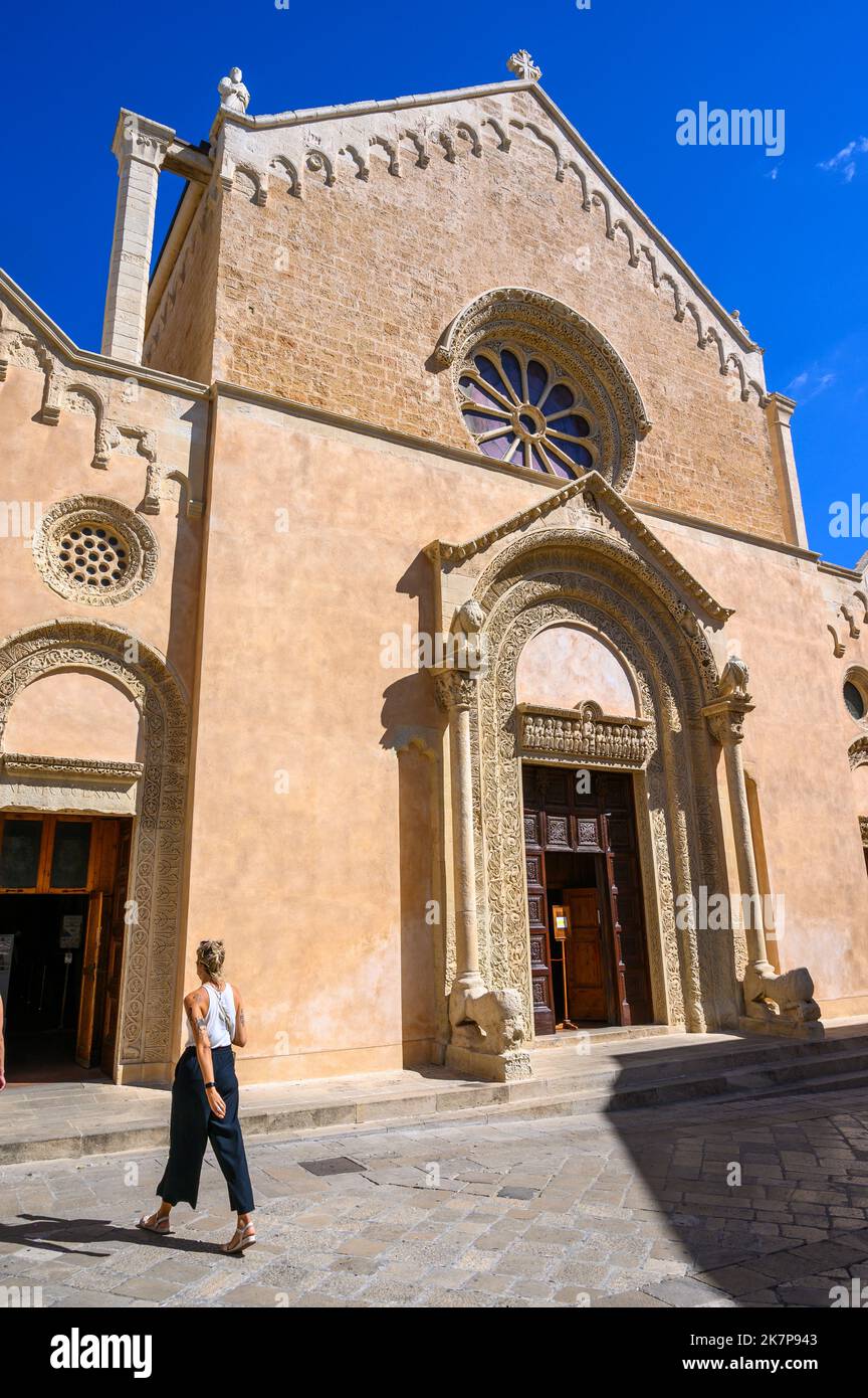 A stylish, young Italian woman walks in front of the Basilica of Saint Catherine of Alexandria, Galatina, Apulia (Puglia), Italy. Stock Photo