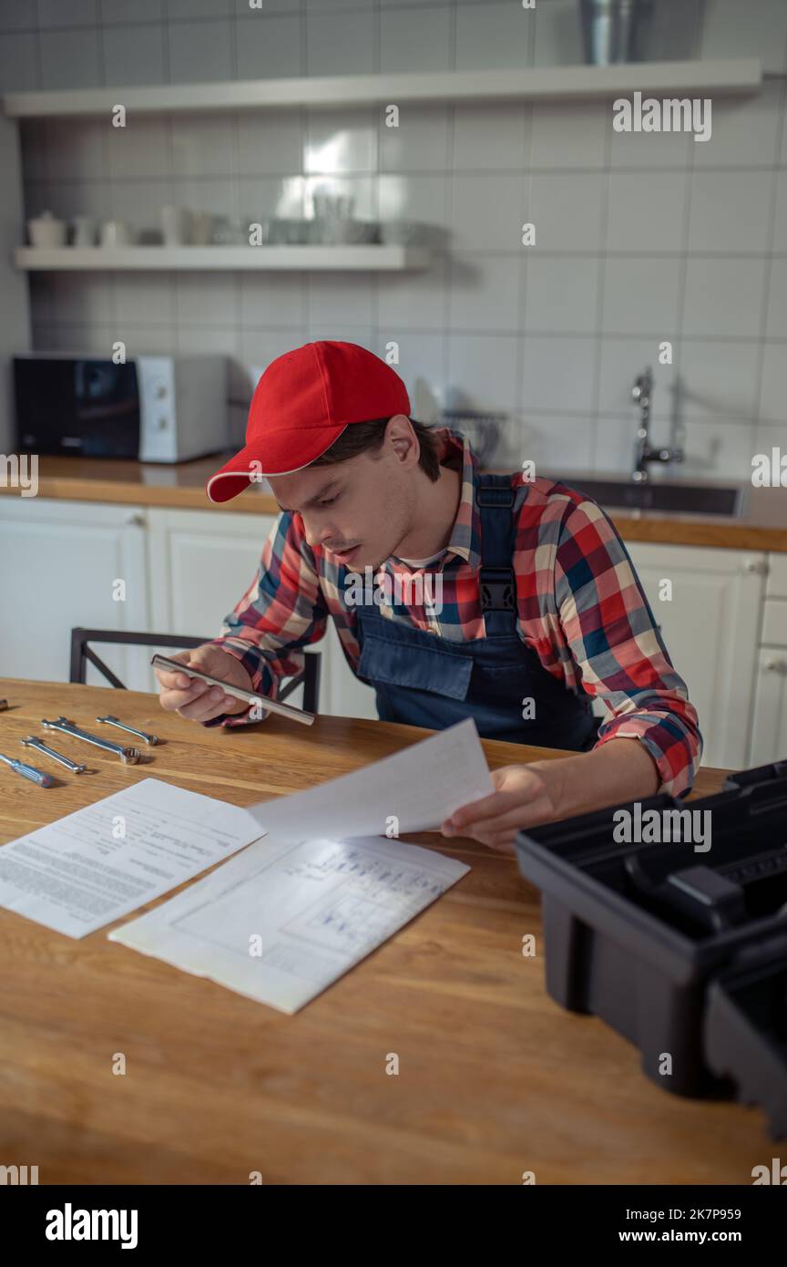 Focused young repairman reading installation instructions in the kitchen Stock Photo