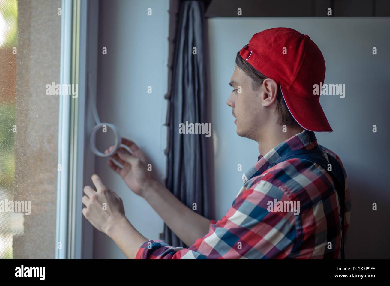 Serious focused repairman engaged in sealing the window Stock Photo