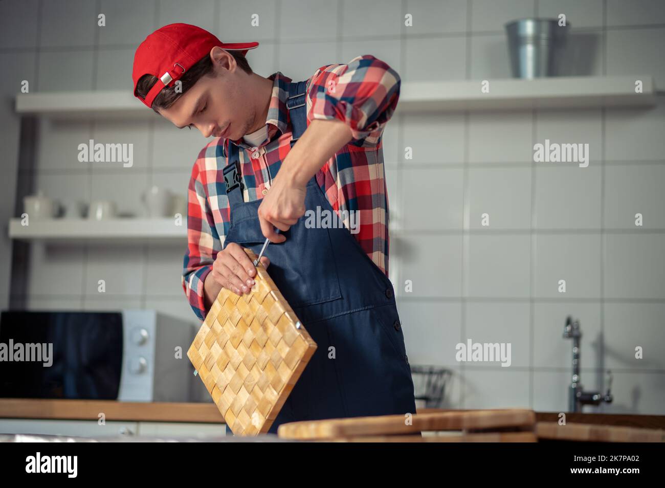 Focused young woodworker making a straw box Stock Photo