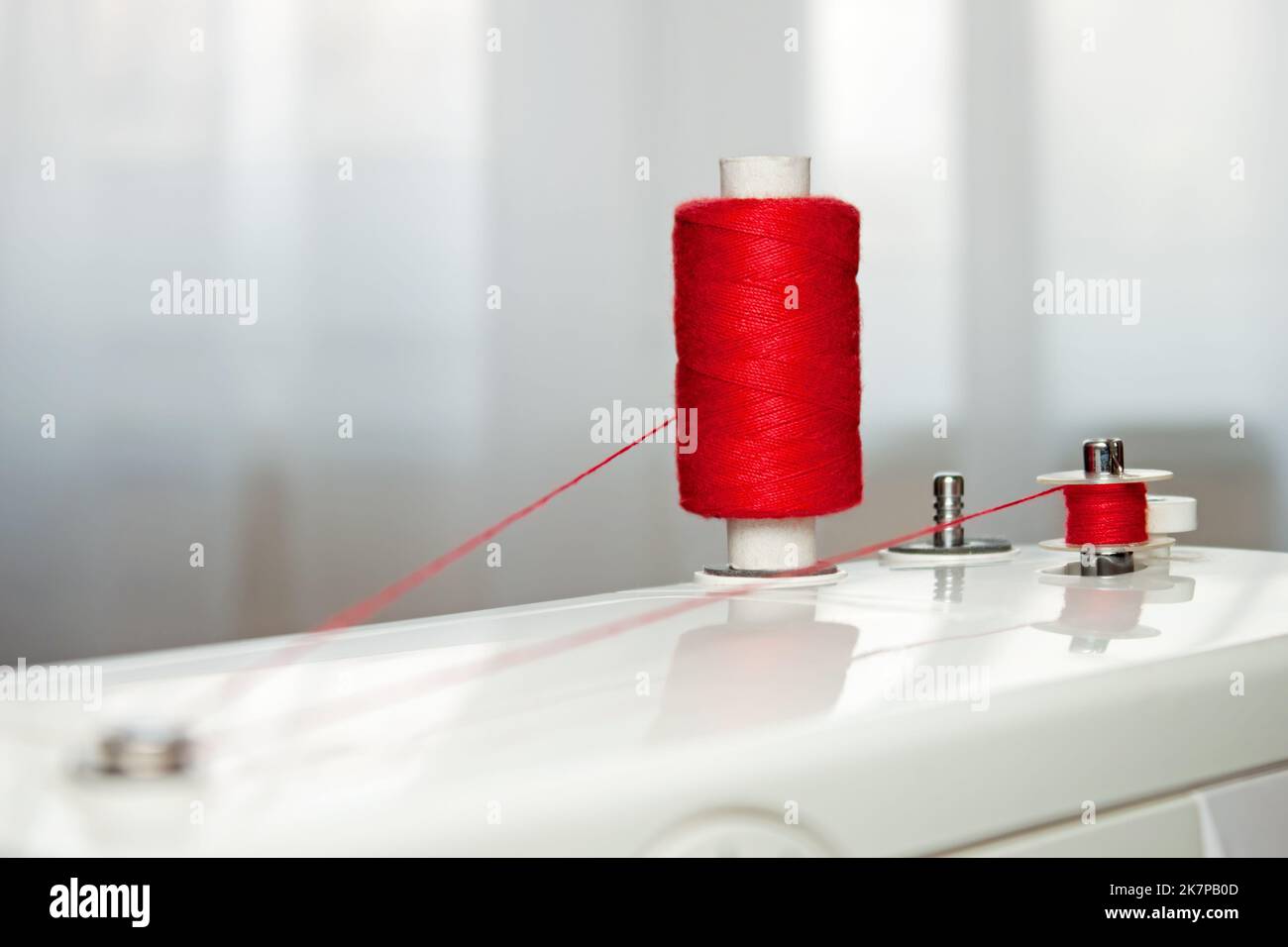 Sewing accessories spool of thread and bobbin with red thread. winding