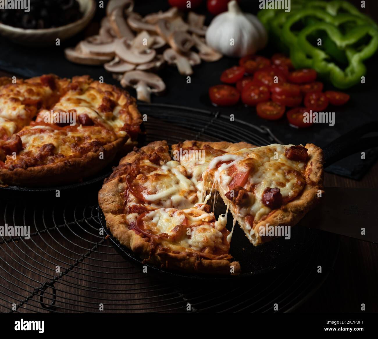 Close up view of two deep dish pan pizzas with a slice being taken from ...