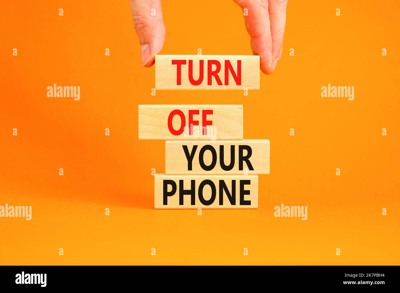 Turn off your phone symbol. Concept words Turn off your phone on wooden blocks. Beautiful orange background. Businessman hand. Business psychological Stock Photo