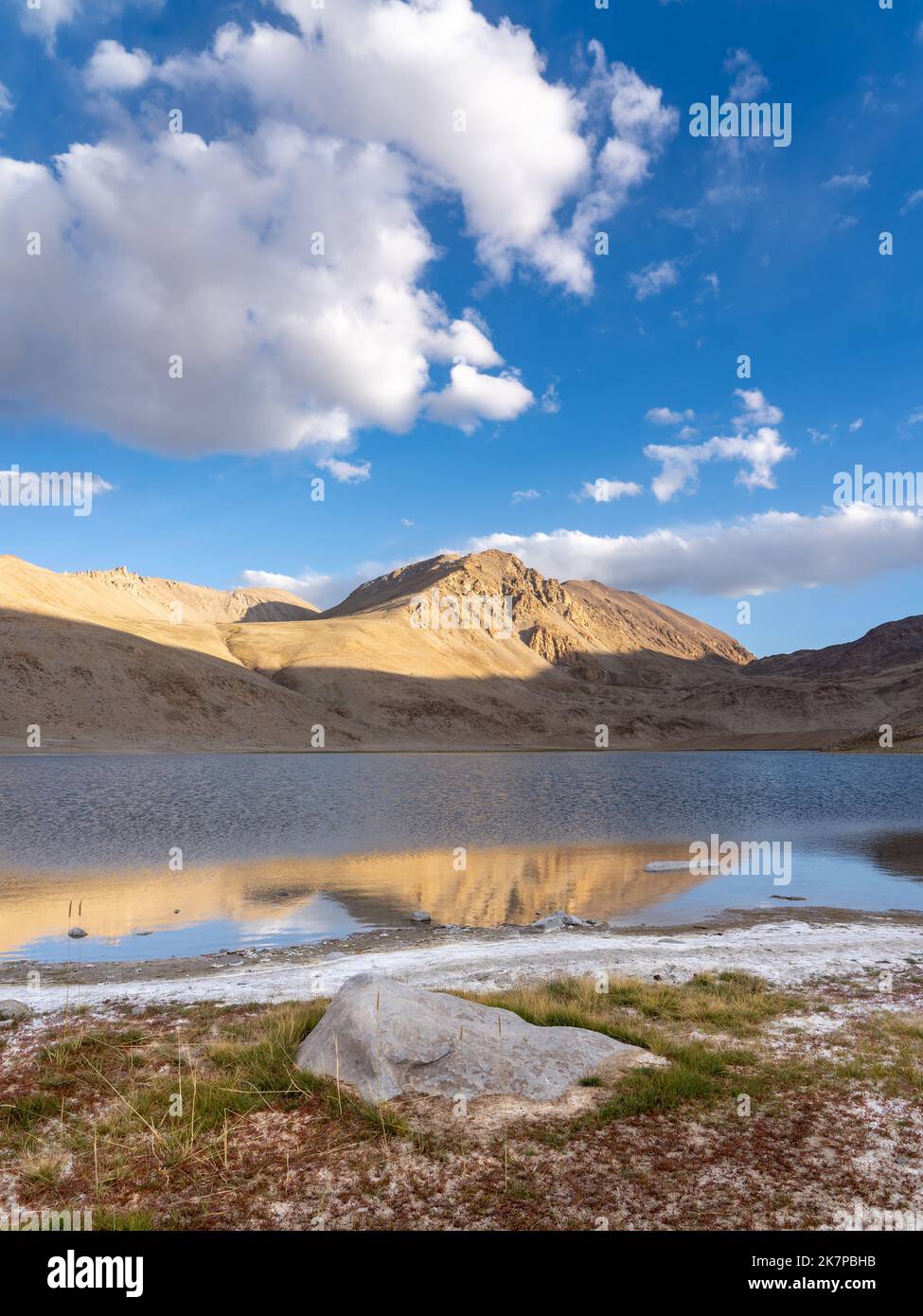 High mountain lake with reflection and salt deposit on shore before sunset between Khargush pass and Pamir Highway, Gorno-Badakshan, Tajikistan Pamir Stock Photo